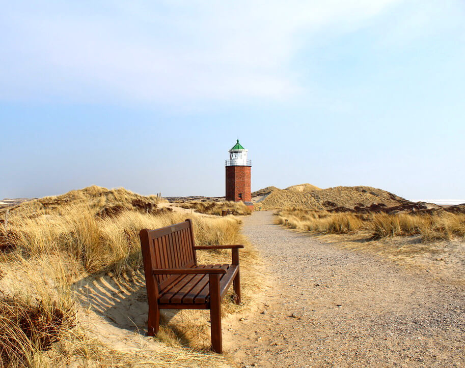 Sitzbank auf Sylt mit Leuchtturm im Hintergrund